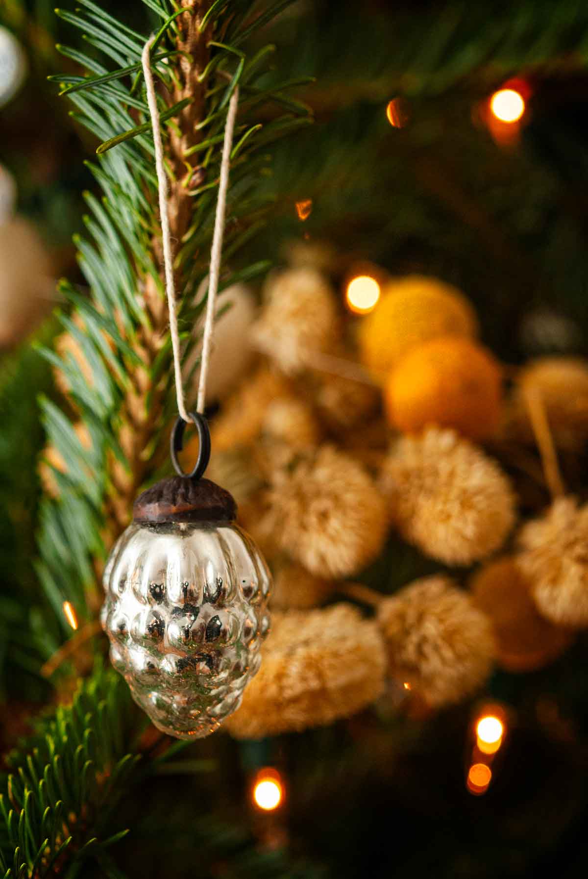 A tiny pinecone ornament in a christmas tree.