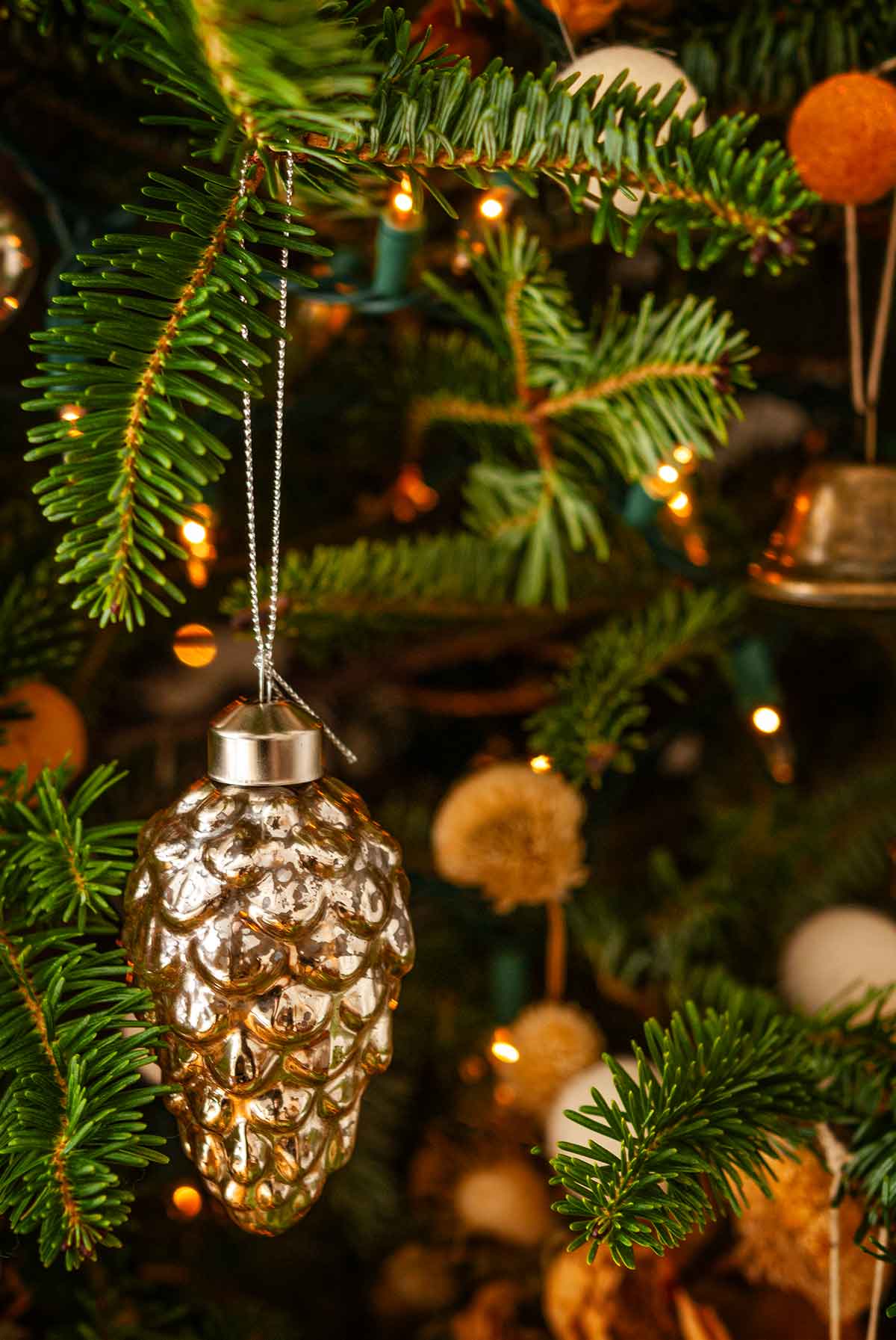 A pinecone-shaped blown glass ornament in a Christmas tree.