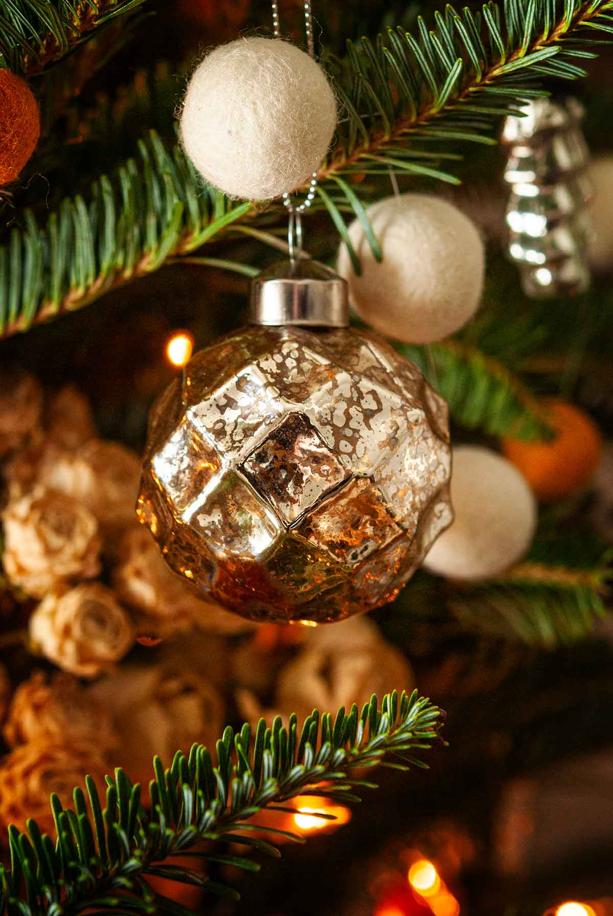 A golden sphere ornament in a Christmas tree.
