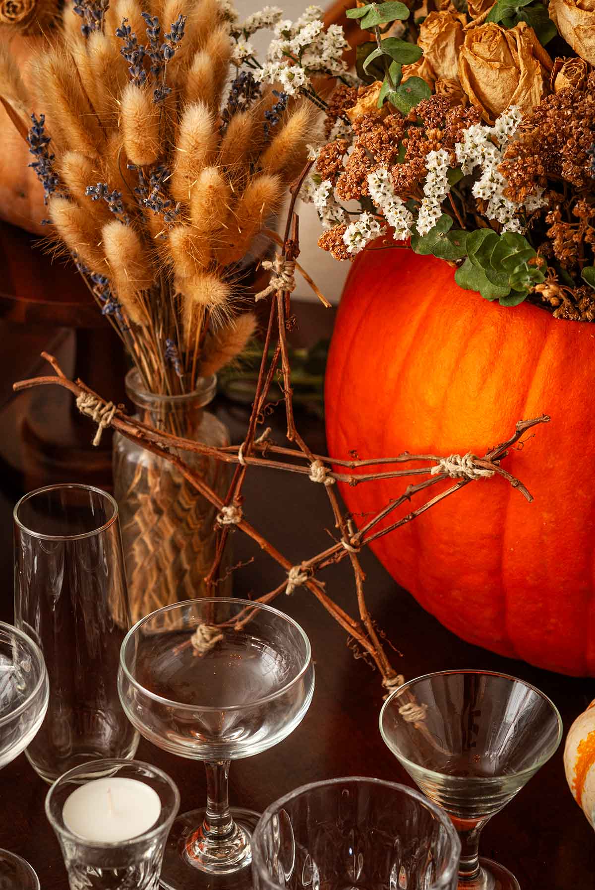 A star made of sticks on a table in front of pumpkins.