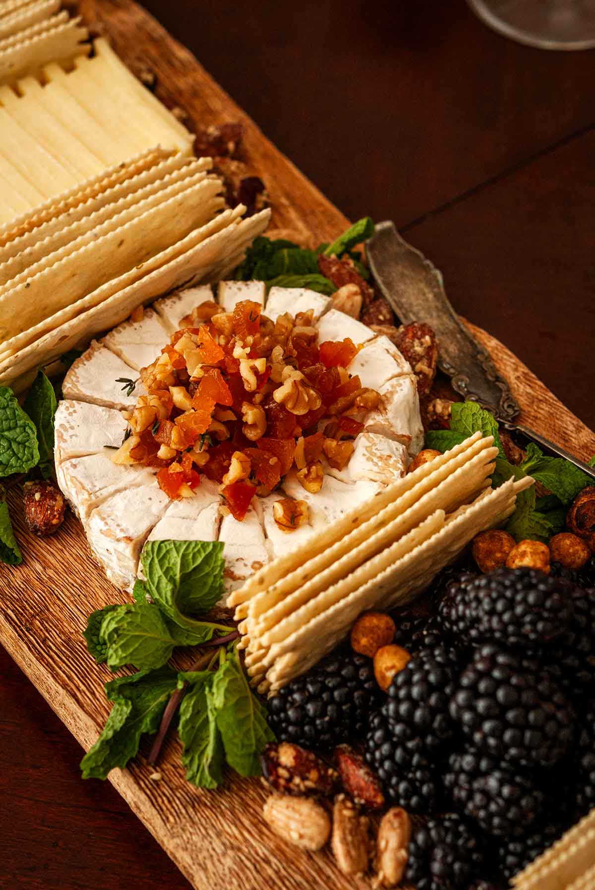 Brie topped with chopped apricots and nuts on a cheese board.